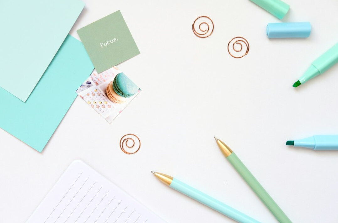 Handwritten notes with a pen on a desk beside a notebook